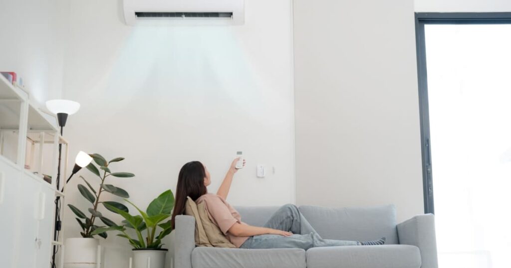 Une femme qui règle son climatiseur dans son salon