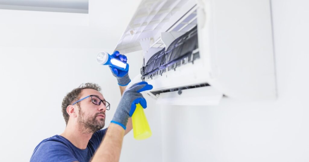 Un professionnel nettoie l'unité intérieure d'un système de climatisation murale. 
