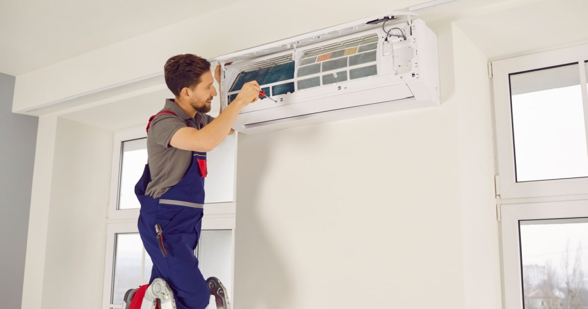 Un spécialiste installe l'unité intérieure d'un système de climatisation dans une maison. 